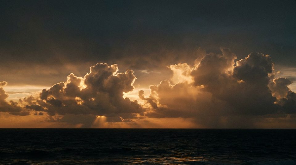 Golden sunset cumulus towering over a dark ocean horizon